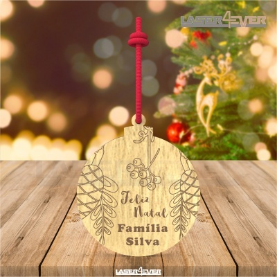 Ornamento de madeira redondo com desenho gravado e texto 'Feliz Natal Família Silva' pendurado com cordão vermelho