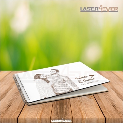 Caderno espiral com capa personalizada com imagem de casal e texto sobre superfície de madeira.