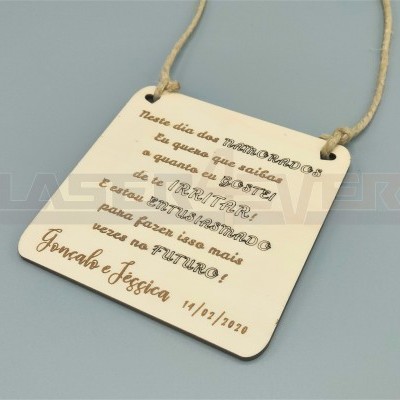 Placa de madeira clara com corda e texto gravado em português com nomes e data.