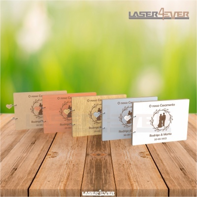 Convites de casamento coloridos sobre mesa de madeira com fundo verde desfocado