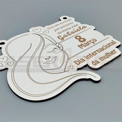 Placa decorativa branca com texto em castanho e linhas douradas representando rosto de mulher.