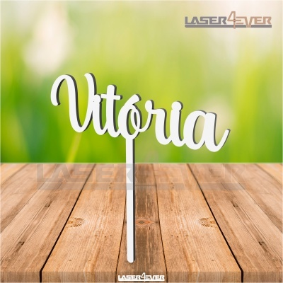 Topo de bolo em madeira com nome Vitória, em fundo verde desfocado