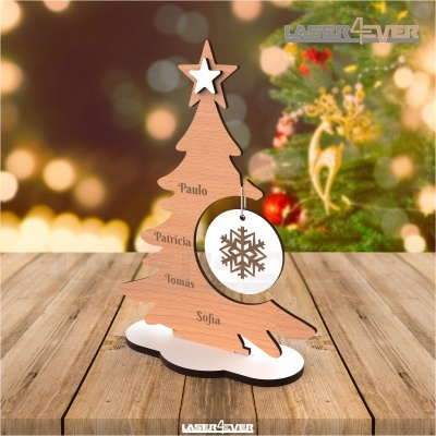 Árvore de Natal em madeira com nomes gravados, pendente com floco de neve, numa mesa de madeira