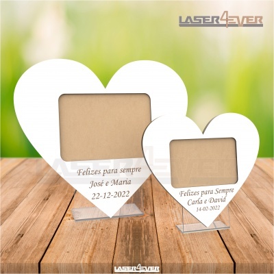 Dois porta-fotos em forma de coração com texto gravado, sobre mesa de madeira