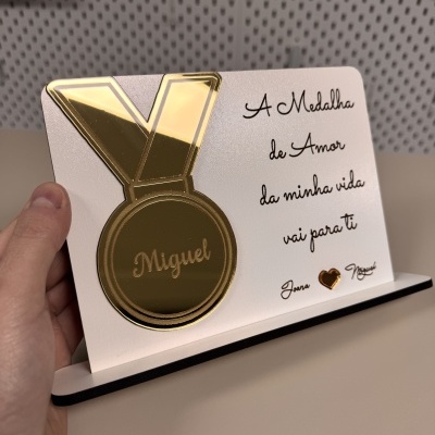 Placa decorativa com medalha dourada e texto em português