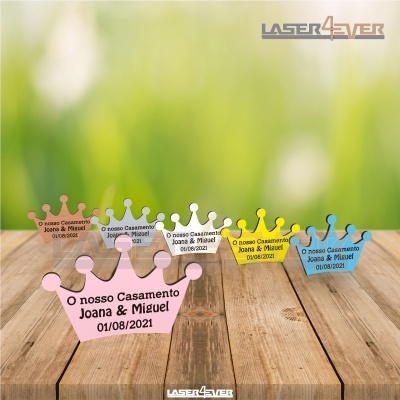 Elementos decorativos em forma de coroa colorida com texto sobre madeira e fundo verde