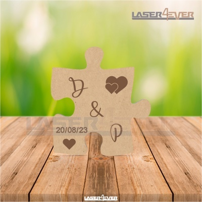 Peça de puzzle em cartão castanho com letras, corações e data em mesa de madeira
