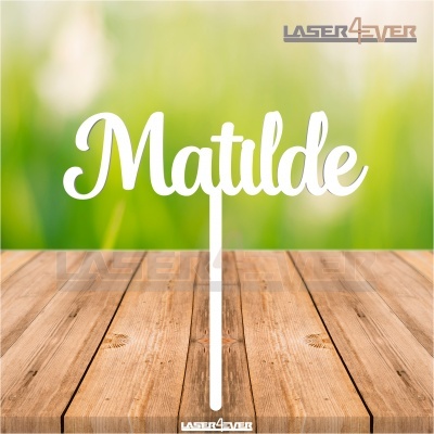 Topper decorativo branco com o nome Matilde em mesa de madeira com fundo desfocado verde e amarelo