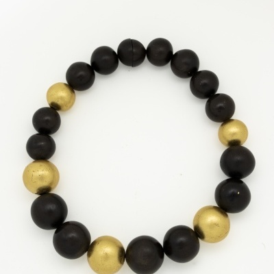 Pulseira com bolas pretas e douradas intercaladas sobre fundo branco