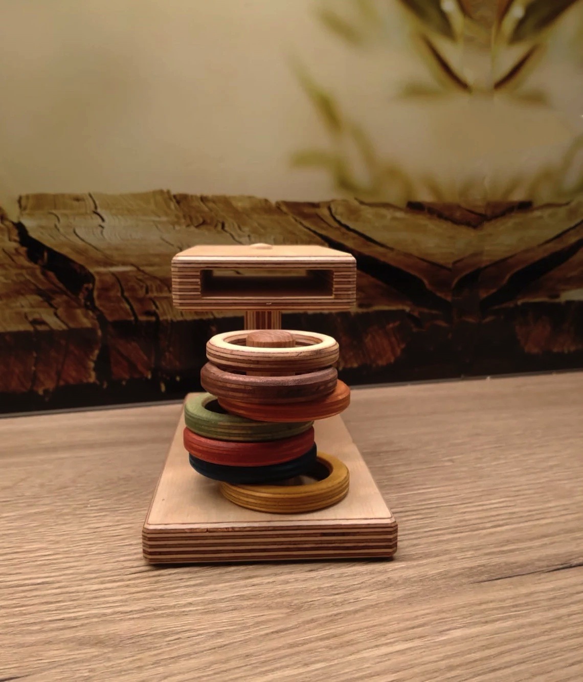 Argolas coloridas de madeira empilhadas numa estrutura de madeira sobre mesa de madeira