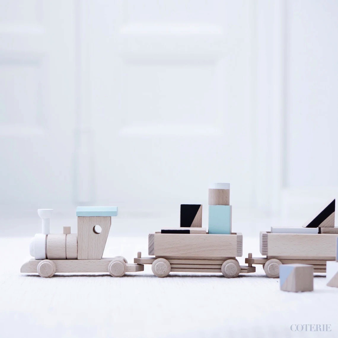 Brinquedo comboio de madeira com formas geométricas coloridas em chão branco
