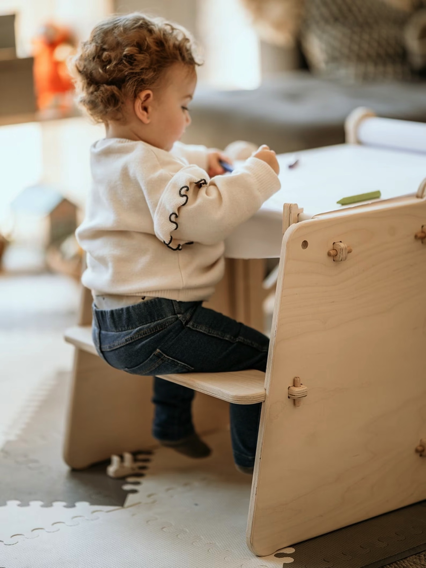 Criança sentada em cadeira de madeira a desenhar numa mesa branca