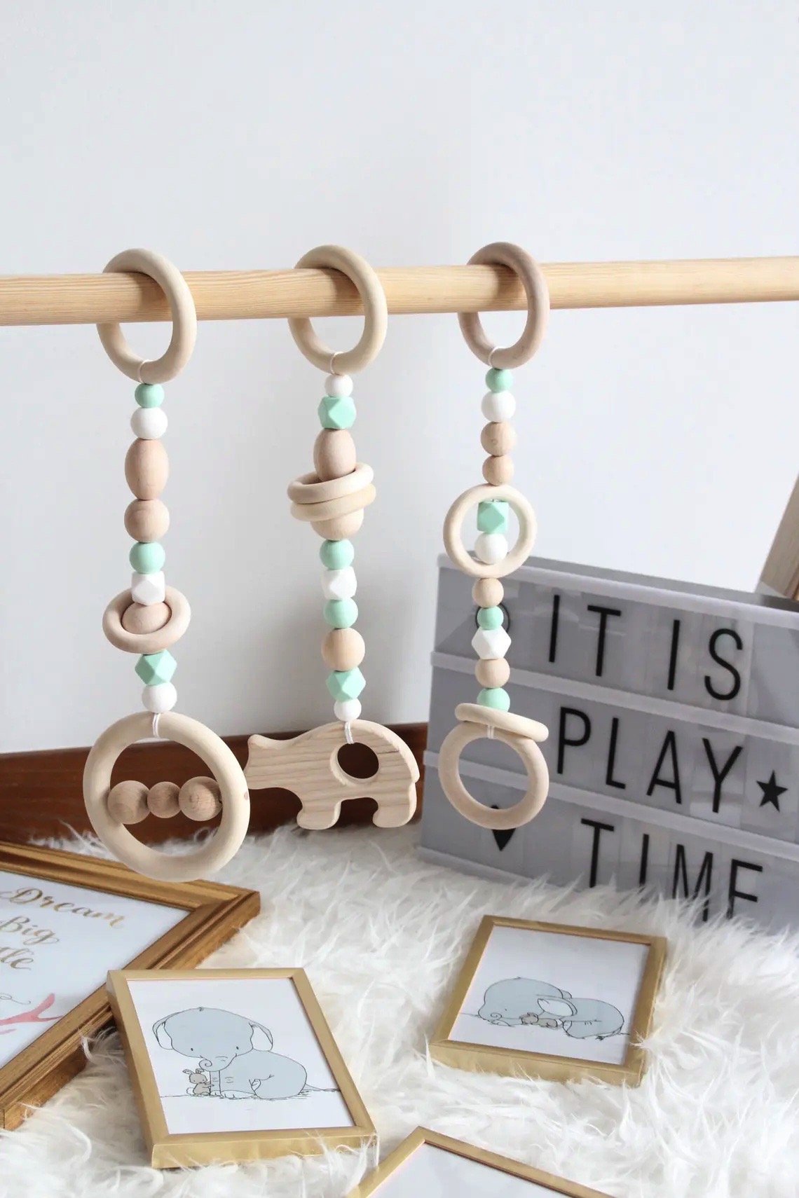 Chocalhos de madeira coloridos pendurados em vara com caixa de luz e quadros infantis no fundo