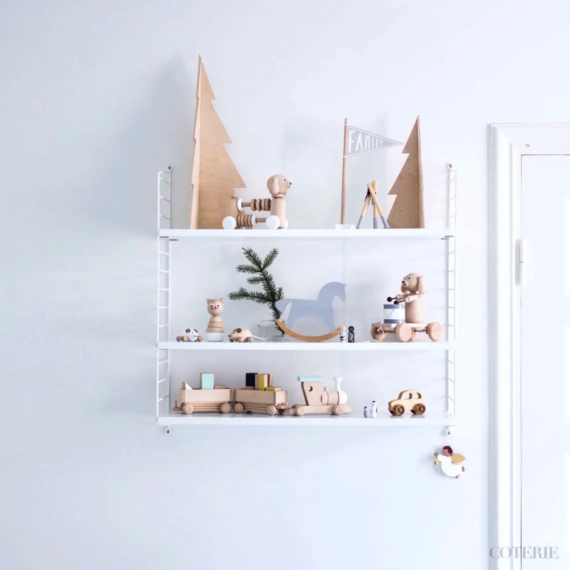 Estantes de parede com brinquedos de madeira natural e decorações em tons claros