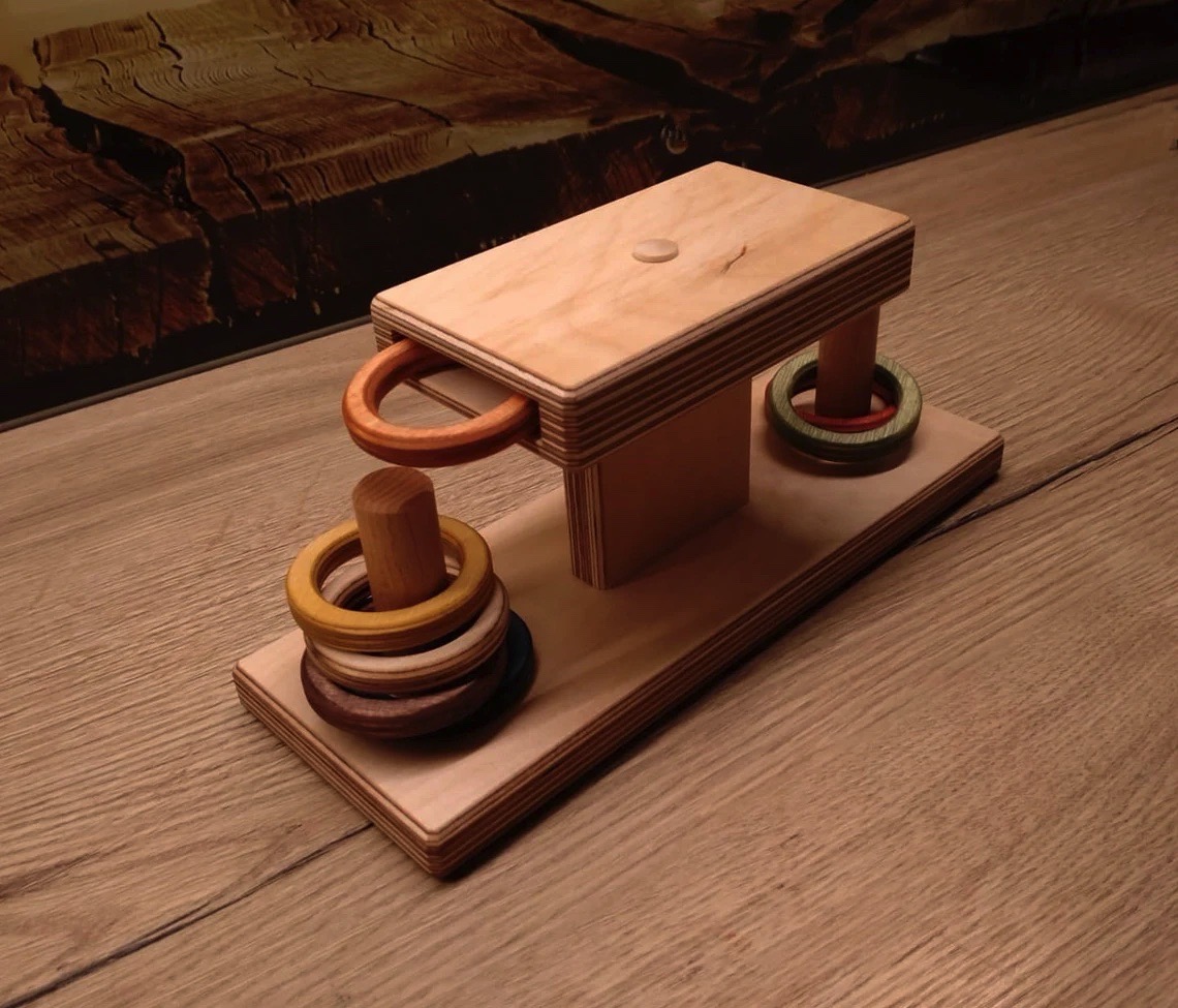 Brinquedo de madeira com anéis coloridos sobre mesa de madeira