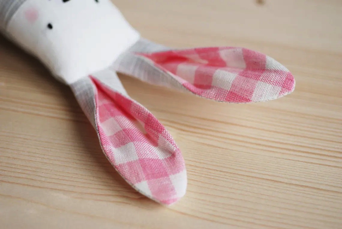 Meias infantis brancas com orelhas à xadrez rosa e branco sobre madeira