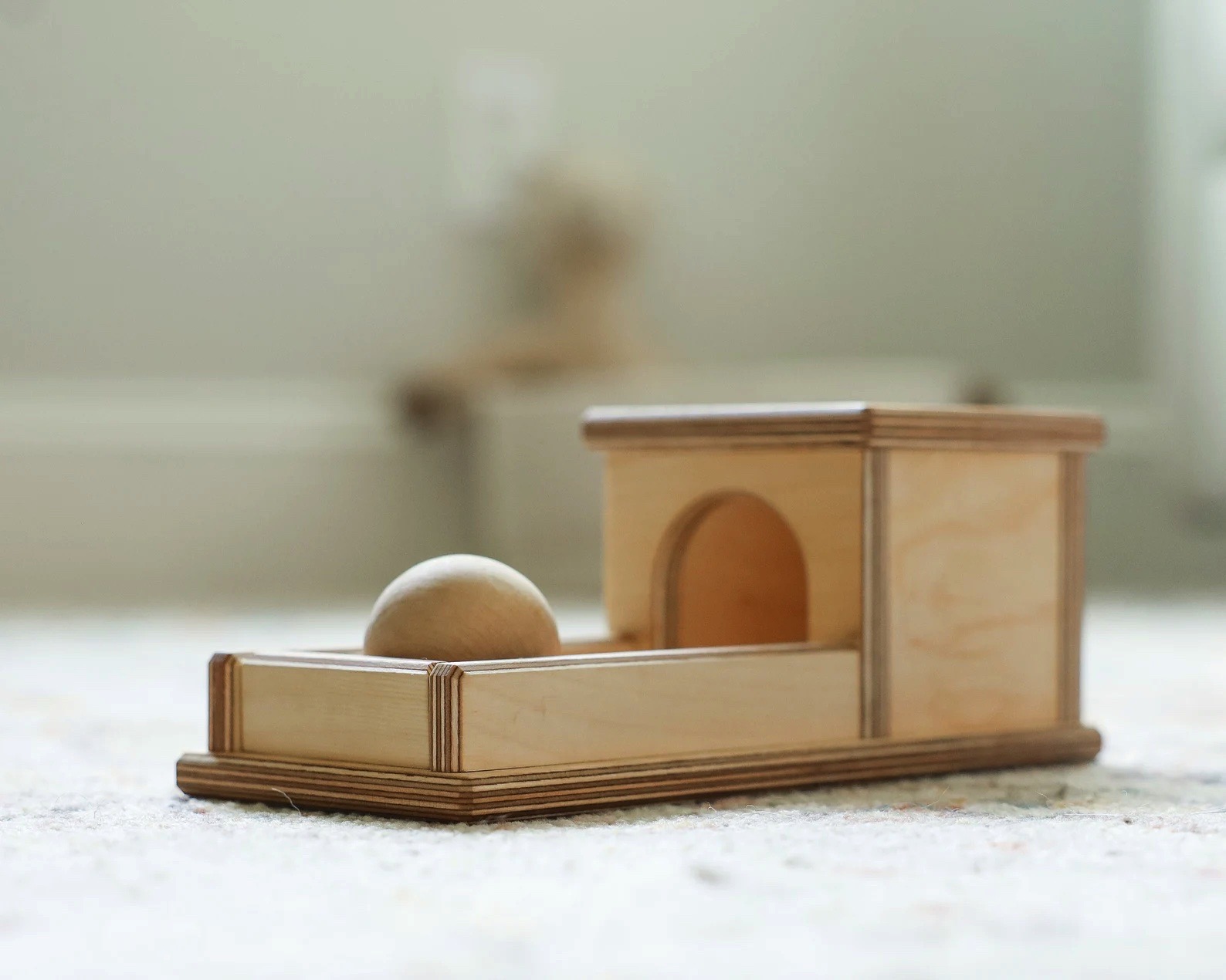 Brinquedo de madeira com uma bola e um castelo pequeno em tons naturais de madeira clara