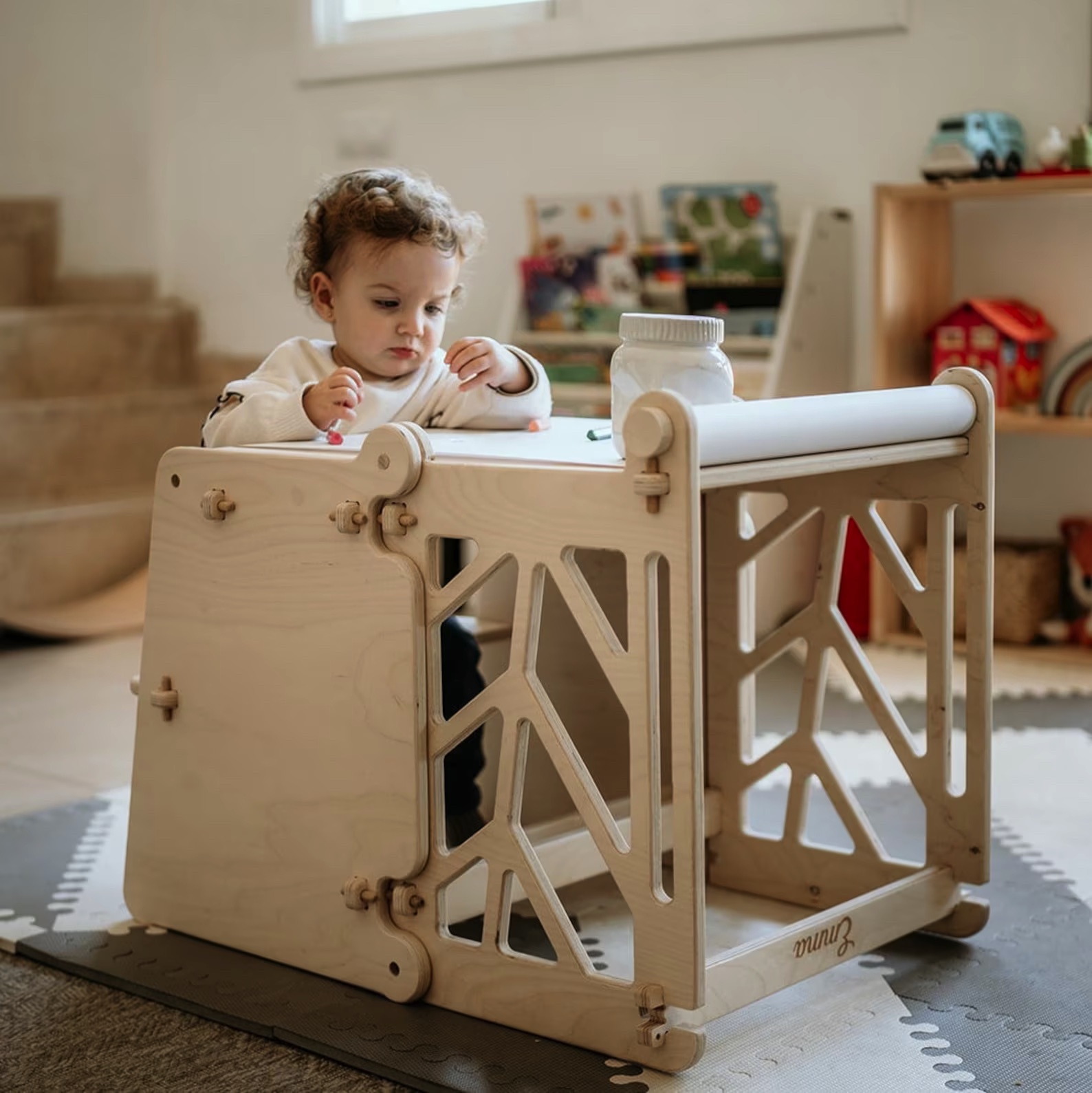 Móvel infantil de madeira clara com recortes geométricos em ambiente interior com criança a brincar