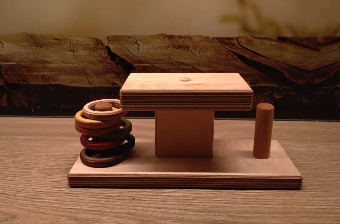 brinquedo de madeira com anéis coloridos sobre base retangular