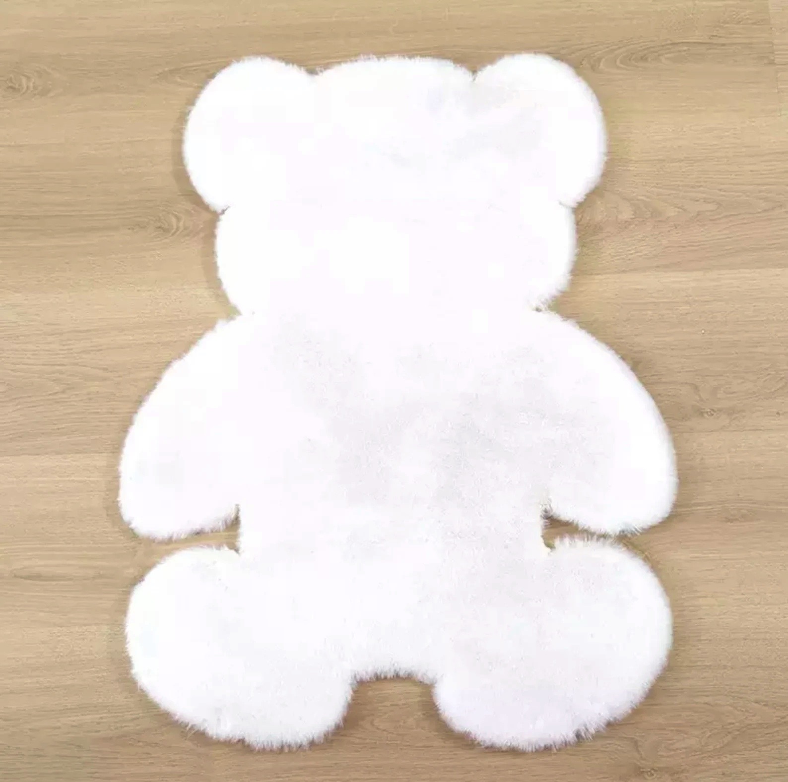 Tapete branco em forma de urso sobre chão de madeira