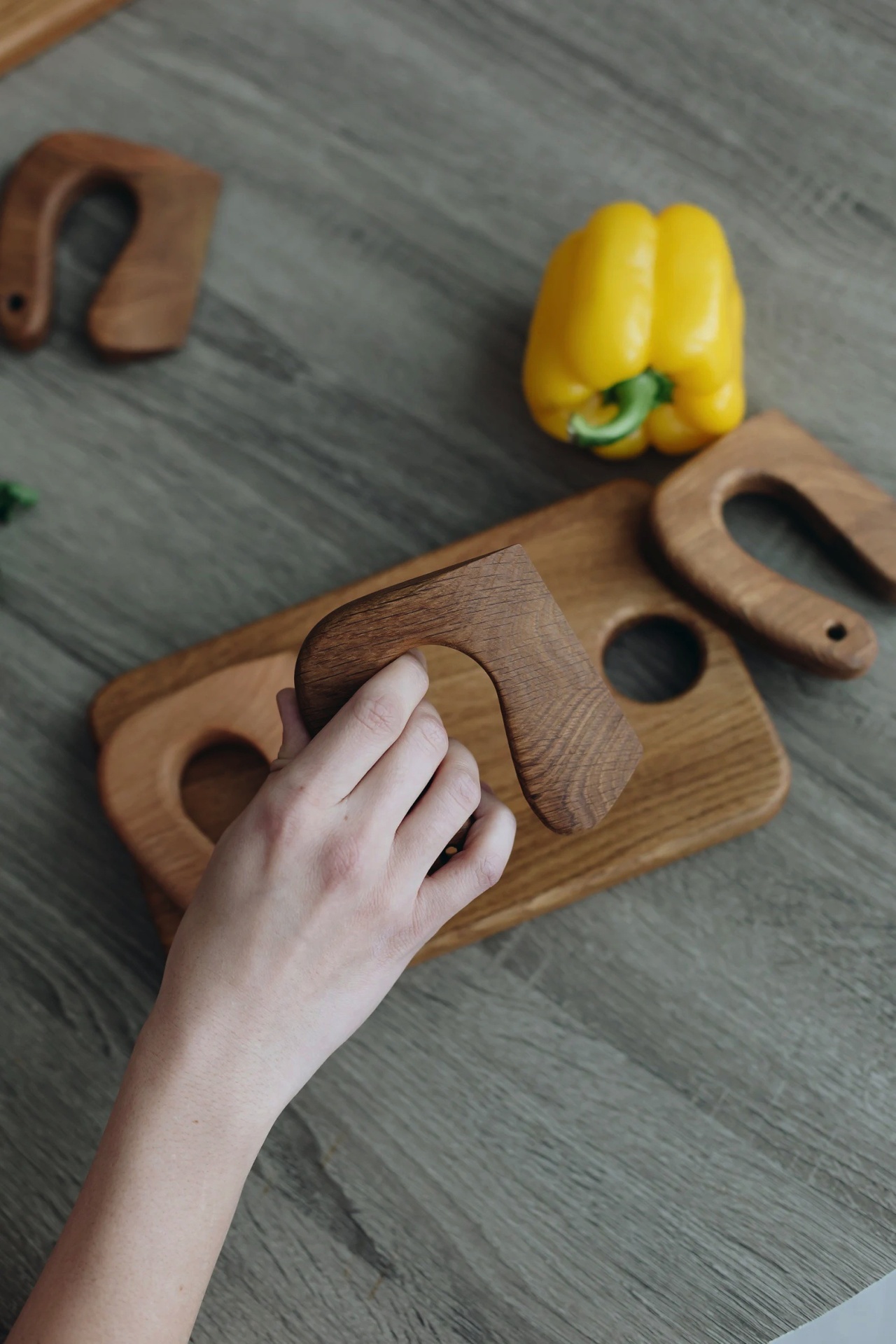 Utensílios e tábuas de madeira com pimento amarelo numa superfície cinzenta