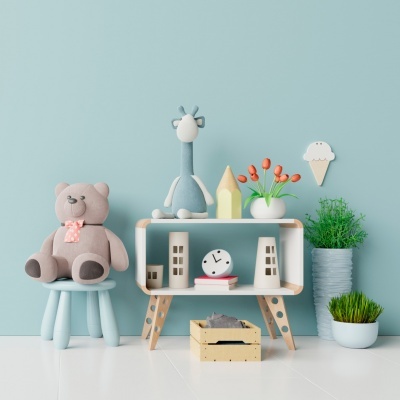 Decoração infantil com urso de peluche, girafa de tecido, estante com relógio e plantas, parede azul clara