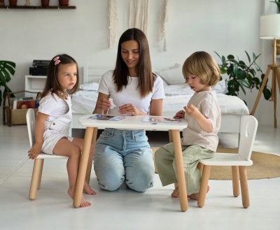Conjunto de mesa e cadeiras infantis brancas com pés em madeira clara em sala de estar clara