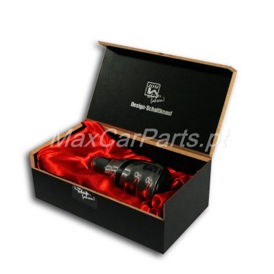 Peça automóvel preta com detalhes vermelhos numa caixa preta com interior vermelho