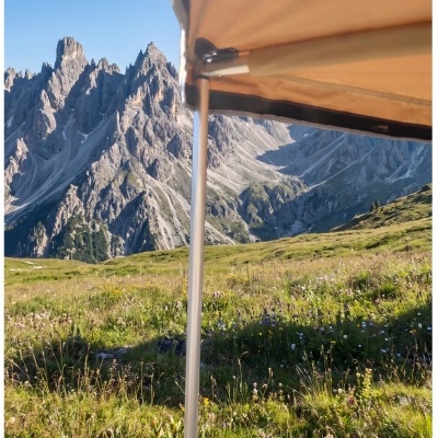 Toldo bege com suporte metálico em paisagem montanhosa