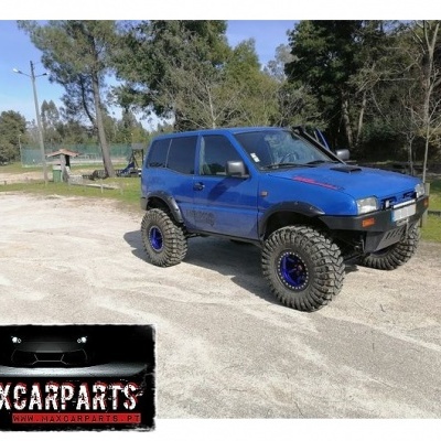 Veículo todo-o-terreno azul com pneus grandes em estrada de terra, logo MAXCARPARTS