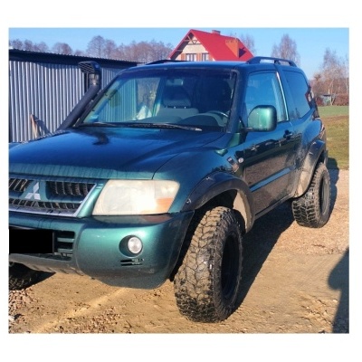 SUV verde escuro com pneus altos e jantes negras ao ar livre