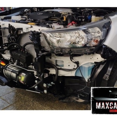 Veículo branco com pára-choques dianteiro removido, mostrando peças internas mecânicas