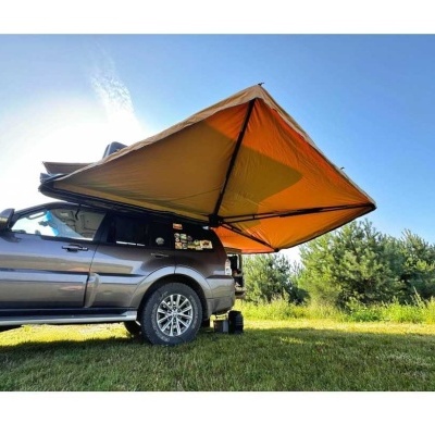 Tenda de campismo castanha no tejadilho de SUV cinzento na relva