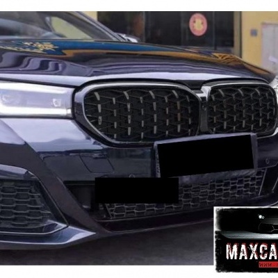 Dianteira de carro escuro com grelha preta e logótipo, faróis modernos, e autocolante MAXCARPARTS ao fundo