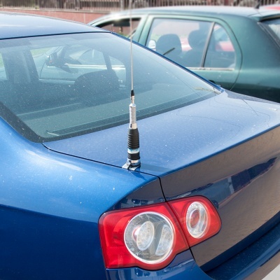 Parte traseira de carro azul com farol vermelho e antena prateada