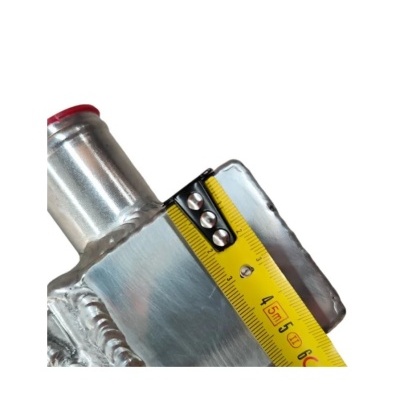 Peça metálica prateada com fita métrica amarela e tubo com tampão vermelho