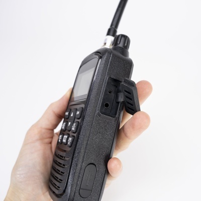 Rádio comunicador portátil preto com ecrã e teclado segurado por uma mão