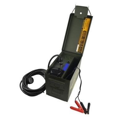 Dispositivo eletrônico preto numa caixa metálica verde com cabos e garras vermelhas e pretas