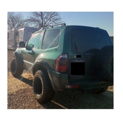 SUV Mitsubishi Pajero verde escuro com pneus todo-o-terreno e roda sobressalente na porta traseira