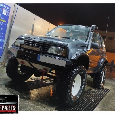 Veículo Suzuki Jimny cinza com pneus off-road grandes e snorkel preto