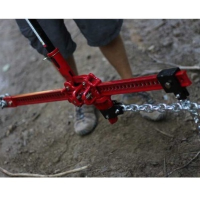 Esticador de correntes vermelho com correntes de aço no chão de terra