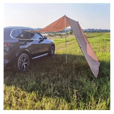 Toldo castanho ao lado de carro preto em campo verde