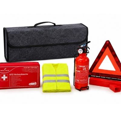 Conjunto de segurança para carro com mala cinzenta, colete amarelo, extintor, triângulo refletor e estojo vermelho.