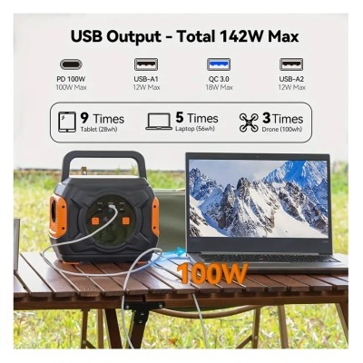 Estação de energia portátil negra e laranja ligada a portátil numa mesa exterior com texto de saídas USB