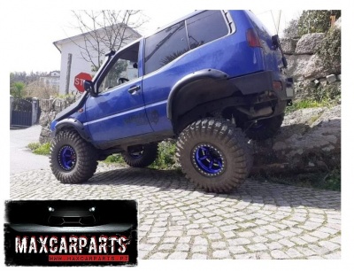 Veículo todo-o-terreno azul com pneus grandes em rua de calçada e logotipo MAXCARPARTS