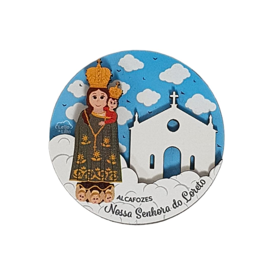 Imã redondo com imagem de Nossa Senhora do Loreto e igreja branca sob céu azul e nuvens