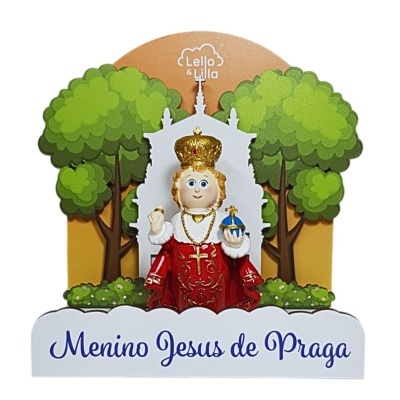 Figura decorativa do Menino Jesus de Praga com coroa dourada, roupa vermelha e árvores verdes ao fundo