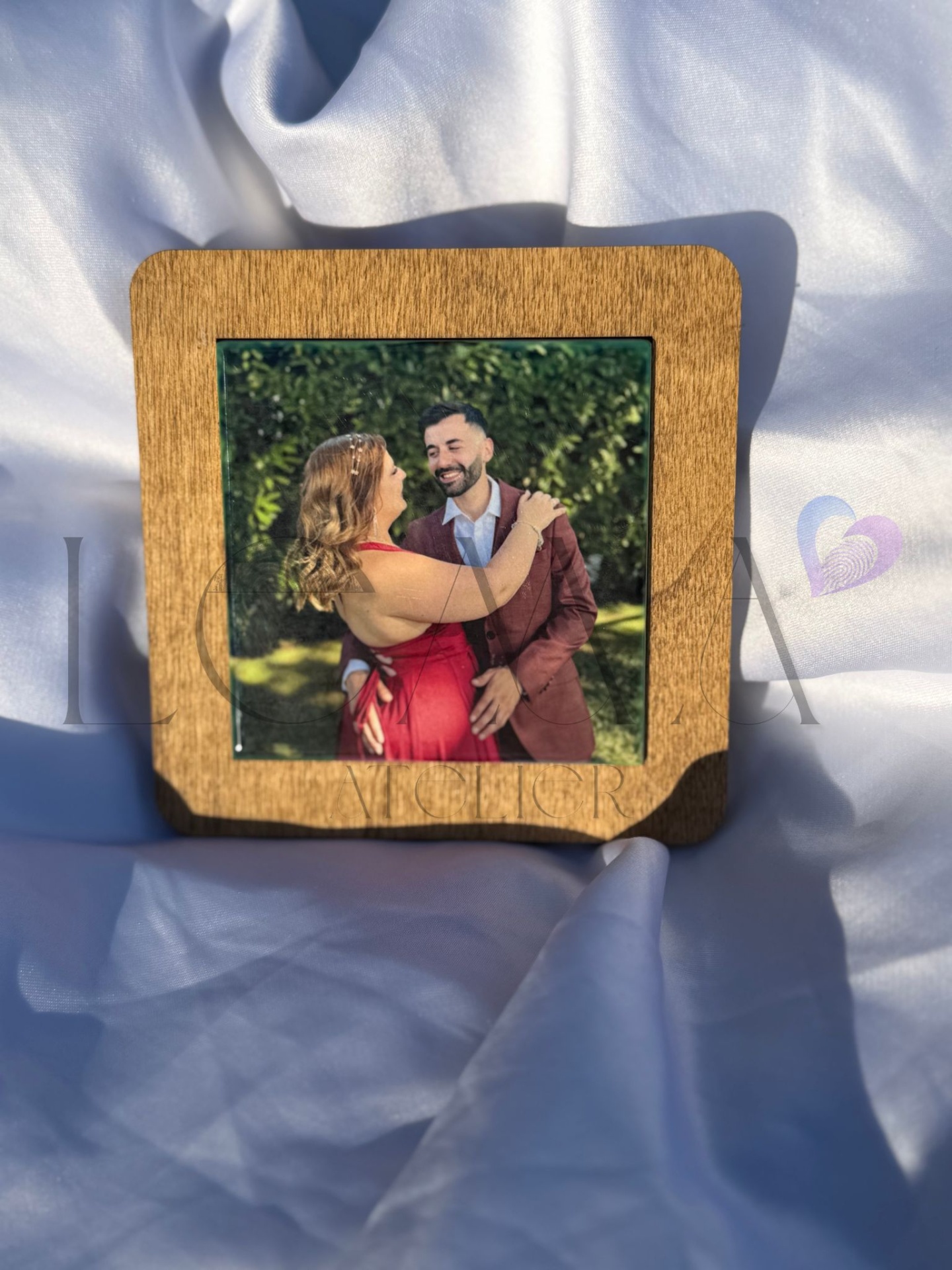 Moldura de Madeira com Azulejo Personalizado — Fotografia Moldura de madeira com fotografia de casal abraçado ao ar livre sobre tecido branco.