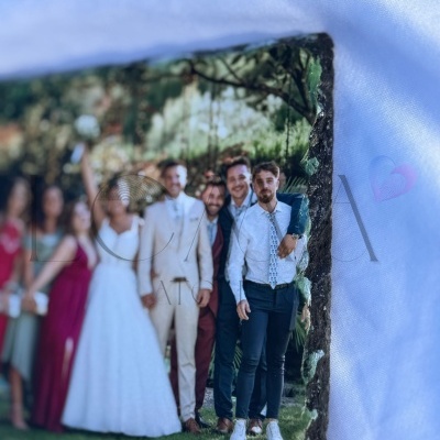 Imagem desfocada numa peça com borda irregular com grupo de pessoas vestidas formalmente em ambiente exterior
