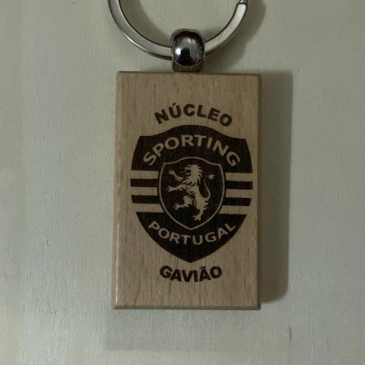 Chaveiro de madeira clara com anel metálico prateado e gravação preta do logo do Sporting Portugal